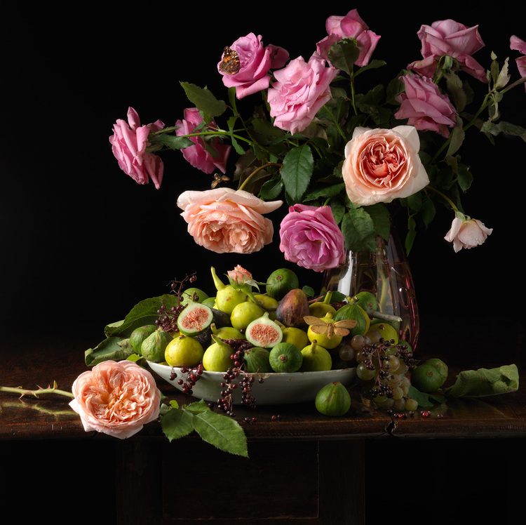 A vase with beautiful flowers and fresh figs arranged inside